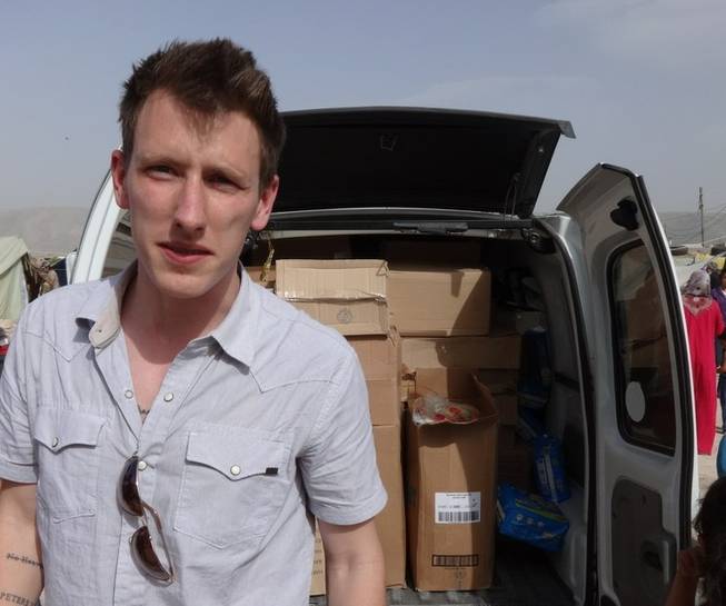 This undated file photo provided by the Kassig family shows Peter Kassig standing in front of a truck filled with supplies for Syrian refugees. A new graphic video purportedly produced by Islamic State militants in Syria released Sunday, Nov. 16, 2014, claims U.S. aid worker Kassig was beheaded.
