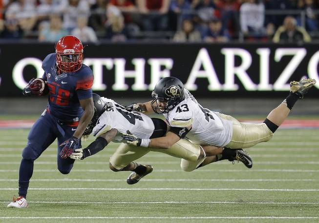 Arizona running back Nick Wilson (28) breaks away from Colorado defensive back Terrel Smith (41) and linebacker Brady Daigh (43) during the second half of an NCAA college football game, Saturday, Nov. 8, 2014, in Tucson, Ariz. (AP Photo/Rick Scuteri)