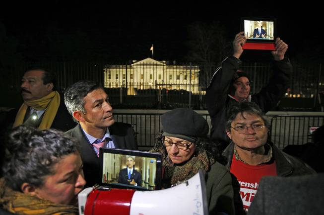 Rosa Lozano, from Washington, left, translates the speech into Spanish as others listen to President Obama's speech on tablets, during a demonstration in front of the White House in Washington, Thursday, Nov. 20, 2014. President Barack Obama announced executive actions on immigration during a nationally televised address. 