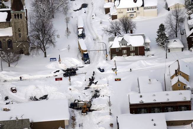 Cars make their way through South Buffalo, N.Y.,Wednesday, Nov. 19, 2014. The Buffalo area found itself buried under as much as 5½ feet of snow Wednesday, with another lake-effect storm expected to bring 2 to 3 more feet by late Thursday.