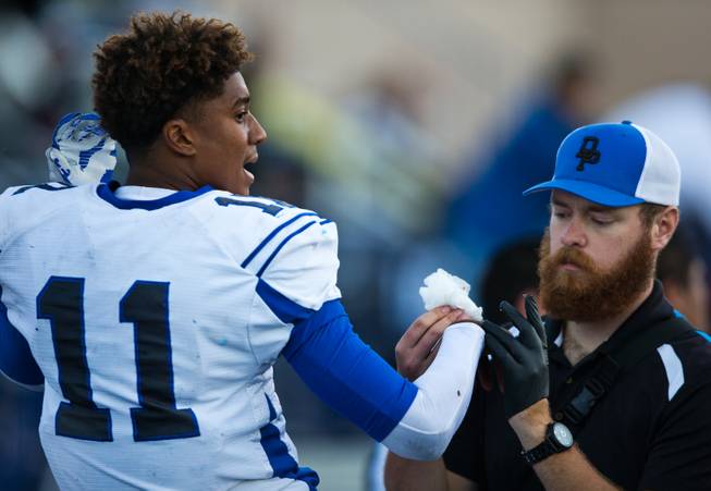 Desert Pines QB Markell Grayson #11 has a cut attended to on the sidelines during the Division I-A state high school football championship game on Saturday, November 22, 2014.