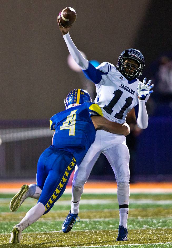 Desert Pines QB Markell Grayson #11 works to get off a pass as Moapa Valley's Kaleb Bodily #4 hits him during the Division I-A state high school football championship game on Saturday, November 22, 2014.