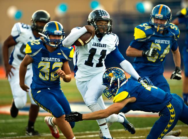 Desert Pines QB Markell Grayson #11 cuts to evade  Moapa Valley's Kaleb Bodily #4 and  in the Division I-A state high school football championship game on Saturday, November 22, 2014.