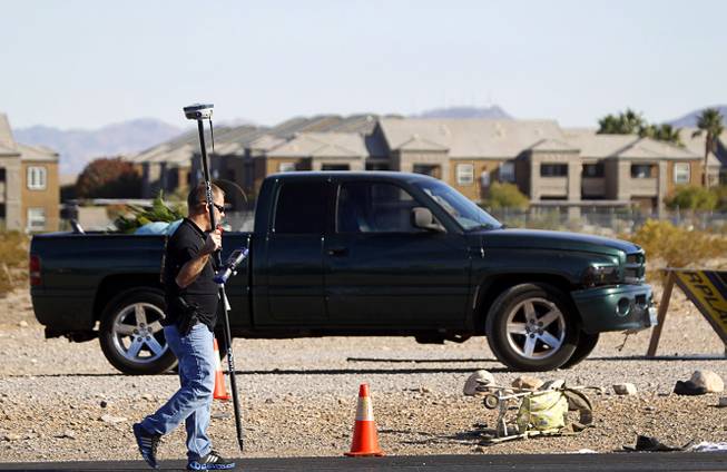 An investigator walks by the area where a man and a baby were hit by a car on South Rainbow Boulevard near Warm Springs Road Monday, Nov. 24, 2014. 