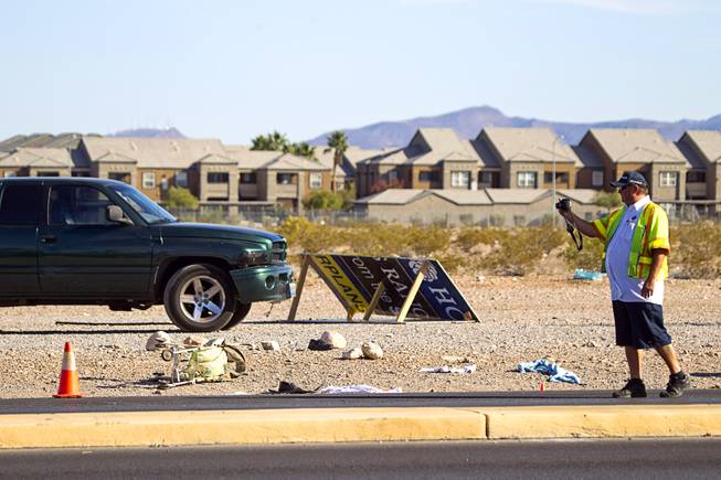 A man takes a photo where a man and a baby were hit by a car on South Rainbow Boulevard near Warm Springs Road Monday, Nov. 24, 2014.