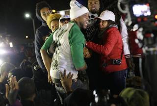 Lesley McSpadden, the mother of Michael Brown, left standing on the top of a car, reacts as she listens to the announcement of the grand jury decision Monday, Nov. 24, 2014, in Ferguson, Mo. A grand jury has decided not to indict Ferguson police officer Darren Wilson in the death of Michael Brown.