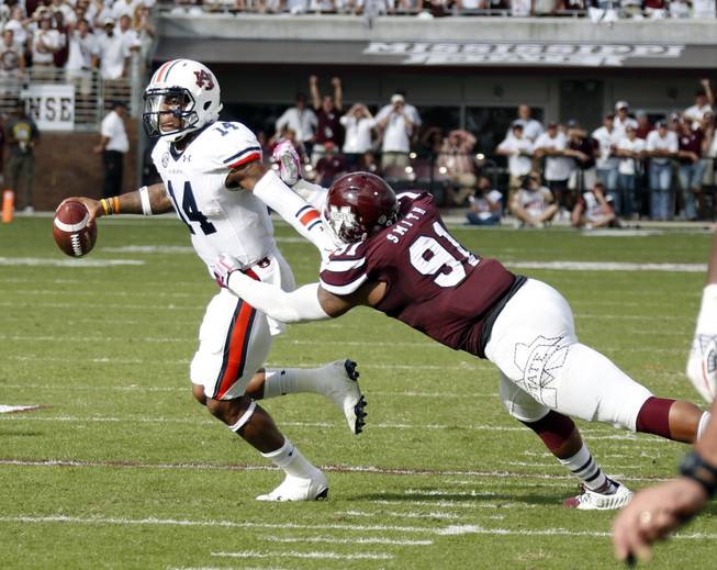 Auburn quarterback Nick Marshall (14) pulls away from the grasp of Mississippi State defensive lineman Preston Smith (91) in the first half of their NCAA college football game in Starkville, Miss., Saturday, Oct 11, 2014. No. 3 Mississippi State beat No. 2 Auburn 38-23. (AP Photo/Rogelio V. Solis)