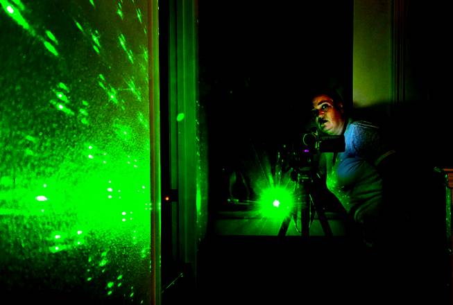 Ghost hunter Jeannine Robertson sets up a camera and laser pen in the darkness during a ghost-hunting expedition in North Las Vegas. The green light is used to detect movement if something passes by. 