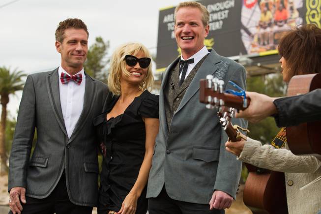 Jack Ryan, Pamela Anderson and Dan Mathews listen to a song by Chrissie Hynde at the Welcome to Fabulous Las Vegas sign Thursday, Nov. 27, 2014. Mathews of People for the Ethical Treatment of Animals married his longtime partner Ryan there in a small wedding party.