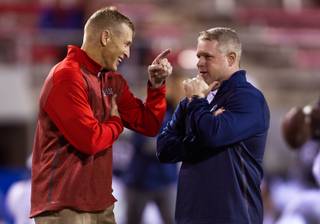 UNLV head coach Bobby Hauck talks lively with Nevada head coach Brian Polian before the start of their game at Sam Boyd Stadium on Friday, November 29, 2014.