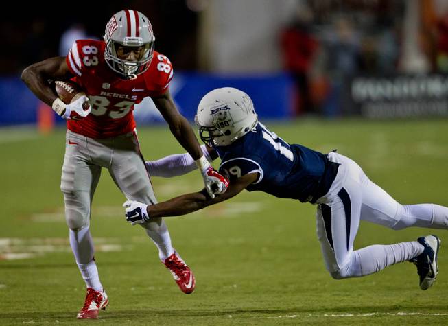 UNLV wide receiver Devonte Boyd (83) fights off a tackle attempt by Nevada defensive back Evan Favors (19) after a catch and run at Sam Boyd Stadium on Friday, November 29, 2014.
