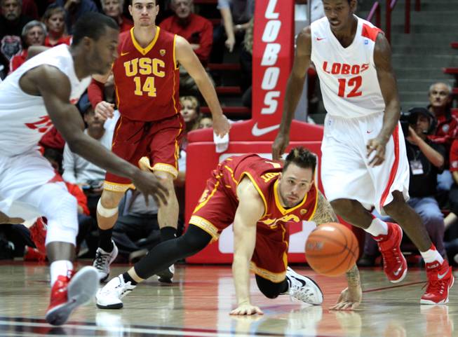 Southern California's Katin Reinhardt loses control of the ball as New Mexico's Sam Logwood, left, and Devon Williams close in during an NCAA college basketball game, Sunday, Nov. 30, 2014, in Albuquerque, N.M. USC won 66-54.