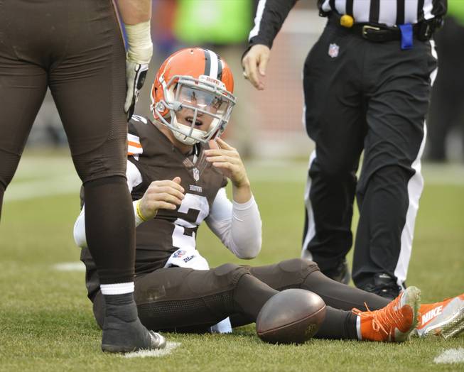Cleveland Browns quarterback Johnny Manziel, center, reacts after being sacked by Cincinnati Bengals defensive tackle Geno Atkins in the third quarter of an NFL football game Sunday, Dec. 14, 2014, in Cleveland.