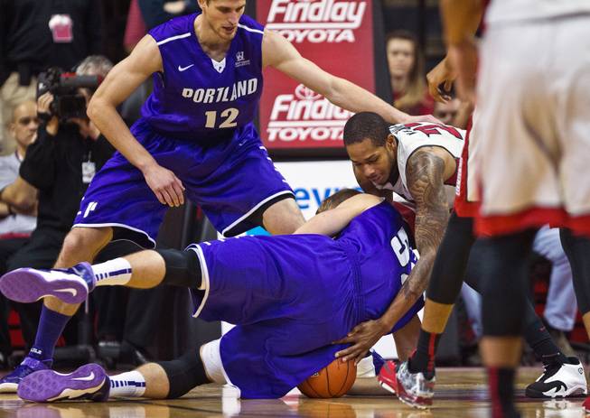 Portland forward/center Volodymyr Gerun (52) falls on a loose ball with UNLV guard Jelan Kendrick (22) attempting to grab it away during their game at the Thomas & Mack Center on Wednesday, December 17, 2014.