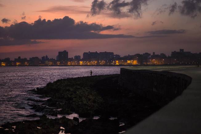 A fisherman casts his line along the Malecon at sunrise in Havana, Cuba, Wednesday, Oct. 8, 2014.