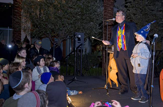 The '"Amazing Arful Roger" performs with the help of volunteer Sammy Dipietro, 7, during a Hanukkah menorah lighting ceremony in The District in Henderson Thursday, Dec. 18, 2014. The event, celebrating the third night of Hanukkah, was organized by Chabad of Green Valley.