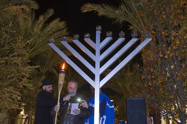 Jack Katz, center, reads a prayer during during a Hanukkah menorah lighting ceremony in The District in Henderson Thursday, Dec. 18, 2014. The event, celebrating the third night of Hanukkah, was organized by Chabad of Green Valley.