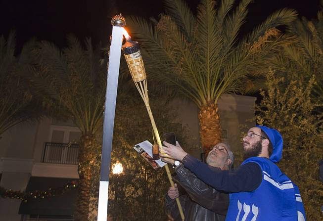 Jack Katz, center, lights a candle during a Hanukkah menorah lighting ceremony in The District in Henderson Thursday, Dec. 18, 2014. The event, celebrating the third night of Hanukkah, was organized by Chabad of Green Valley.