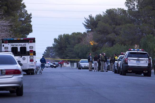 Metro Police officers and investigators gather on Tomkins Avenue after an officer-involved shooting near East Tompkins Avenue and Mohave Road Sunday, Dec. 21, 2014.