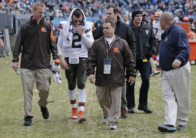 The Cleveland Browns' Johnny Manziel, second from left, is helped off the field after being injured in the first half of an NFL football game against the Carolina Panthers in Charlotte, N.C., on Sunday, Dec. 21, 2014.