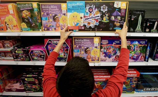 Sales associate Justin Padilla arranges shelves of construction and building toys for girls at a Toys "R" Us store in Los Angeles.