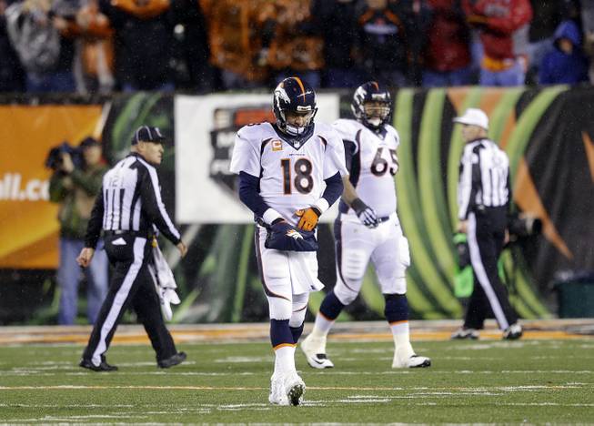 Denver Broncos quarterback Peyton Manning (18) walks off the field after throwing an interception to Cincinnati Bengals cornerback Dre Kirkpatrick who ran it in for a touchdown during the second half of an NFL football game Monday, Dec. 22, 2014, in Cincinnati. The Bengals beat Denver 37-28. 
