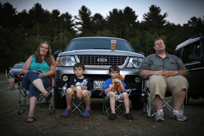 In this photo made Thursday, June 26, 2014, Jen and Philip Mason, along with their sons Skyelar, left, and Trysten, watch the previews at the Saco Drive-In in Saco, Maine. Many in the movie industry feared the need to convert to digital could be the death knell for drive-ins, but drive-in operators are finding creative ways to afford the switch.  Drive-in movie theater operators say more than 200 of the remaining 348 drive-ins in the country have made the expensive conversion from film to digital, which typically costs more than $70,000.  (AP Photo/Robert F. Bukaty)