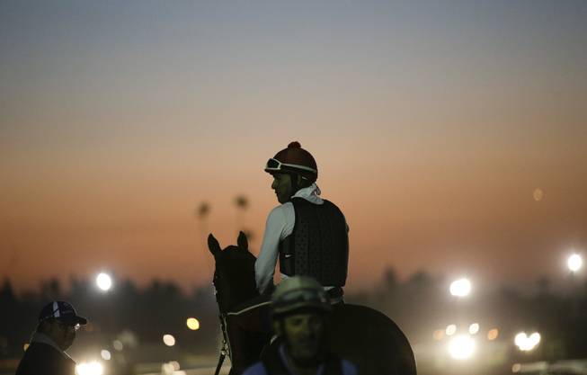Exercise rider Willie Delgado and California Chrome wait for the track to open during morning workouts ahead of the Breeders' Cup Classic horse race at Santa Anita Park Tuesday, Oct. 28, 2014, in Arcadia, Calif. (AP Photo/Jae C. Hong)