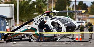 A crime scene investigator works the scene of a LVMPD helicopter down in the street at 23rd Street north of Bonanza Road after a crash landing on Wednesday, December 31, 2014.