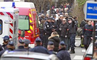 Police officers and rescue workers gather at the scene after gunmen stormed a French newspaper, in Paris, Wednesday, Jan. 7, 2015. Masked gunmen shouting 