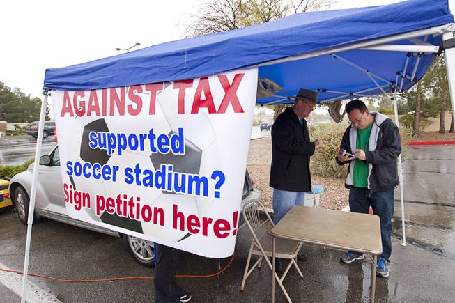 Las Vegas City Councilman Bob Beers, left, looks on as Ari Stotland signs a petition opposing spending taxpayer money on a downtown soccer stadium Sunday, Jan 11, 2015. Opponents need 2,306 signatures to bring the project up for a referendum.