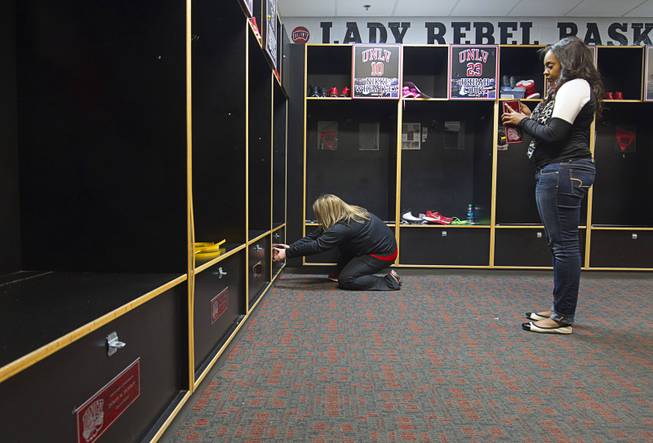 Rachel Dunn, left, director of women's basketball operations, and Lauren Charles, administrative coordinator, add sponsor plaques to lockers in the Lady Rebels locker room at UNLV Thursday, Jan. 15, 2015. Each players' locker is sponsored by a donor for $2,000  one of the many ways the program is being creative to stay afloat.