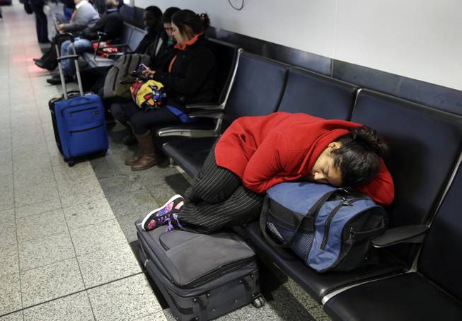 A woman sleeps on top of her luggage at LaGuardia Airport in New York, Monday, Jan. 26, 2015. Airlines canceled thousands of flights into and out of East Coast airports as a major snowstorm packing up to 3 feet of snow barrels down on the region.