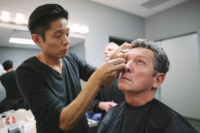 Kazu Tsuji works on the makeup for Bob Anderson, who ...