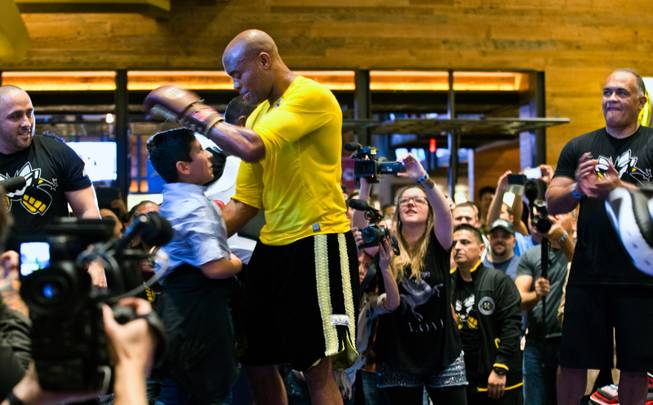 UFC 183 fighter Anderson Silva greets a young fan brought onto the mat during 'workouts' open to the public at the MGM Grand Casino floor on Wednesday, January 28, 2015.