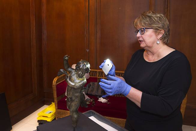 Alex Klingelhofer, vice president of collections for Premier Exhibitions, uses her phone to shine light on a bronze cherub during an installation at "Titanic: The Artifact Exhibition" at the Luxor Thursday, Feb. 5, 2015. The new artifact is believed to be a light fixture from the Titanic's aft grand staircase.