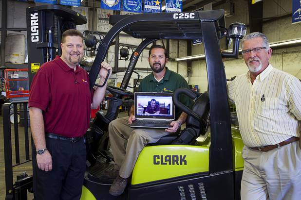 Doug Stout, left, operations manager, Adrian Paris, center, parts manager, and Tim Dixon, sales manager pose on the Inland/Hobbs Material Handling shop floor in Las Vegas Monday, Feb. 9, 2015. Their boss Rick Kwiatkowski, pictured on the laptop, lives in Phoenix. 