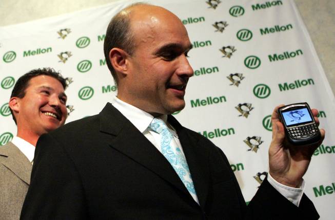 Jim Balsillie, right, chairman and co-CEO of Research in Motion, shows the Pittsburgh Penguins logo on his BlackBerry with Penguins Hall of Famer Mario Lemieux behind him Thursday, Oct. 5, 2006, in Pittsburgh. Lemieux's ownership group agreed to sell the franchise to Balsillie, but the deal fell through when the NHL wouldn't let Balsillie move the team to Hamilton, Ontario.