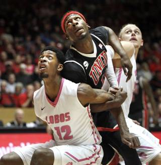 New Mexico's Devon Williams, left, and Hugh Greenwood try to contain UNLV's Goodluck Okonoboh under the basket during the second half of an NCAA college basketball game Saturday, Feb. 21, 2015, in Albuquerque. UNLV won 76-68.