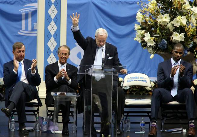 North Carolina basketball coach Roy Williams holds up four fingers as a tribute during a memorial service for former North Carolina basketball coach Dean Smith on Sunday, Feb. 22, 2015, at the Smith Center in Chapel Hill, N.C. Smith died at 83 earlier in February. He was famous for his four-corners offensive strategy.