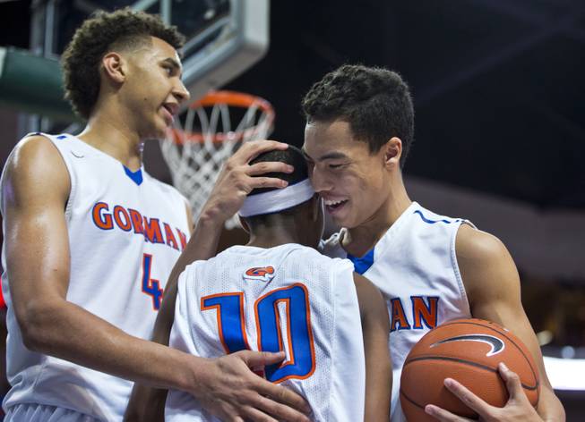 Bishop Gorman's Chase Jeter (4) congratulates teammate Julian Payton (10) for taking a hard foul with more love from Richie Thornton (2) against Palo Verde during the state basketball championship game on Friday, Feb. 27, 2015.