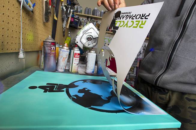 Artist Izaac Zevalking pulls back a stencil from an artwork in his studio Sunday, March 1, 2015, in Summerlin. Zevalking, the artist behind Recycled Propaganda, will be celebrating two years of being with First Friday on March 6.