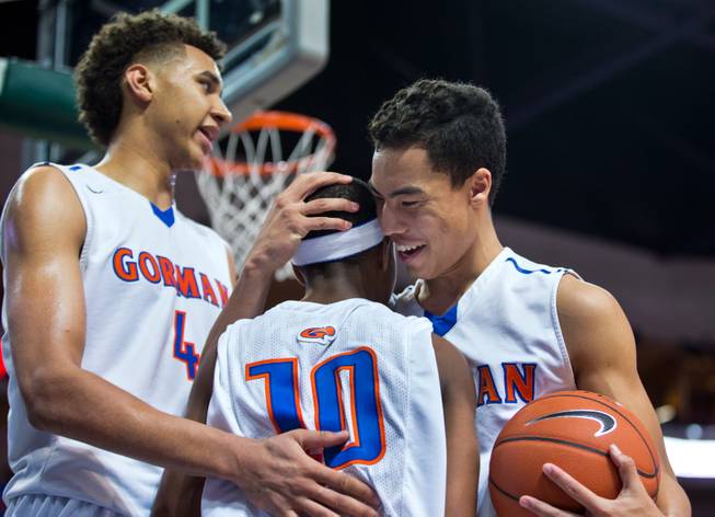 Bishop Gorman's Chase Jeter (4) congratulates teammate Julian Payton (10) for taking a hard foul with more love from Richie Thornton (2) against Palo Verde during the NIAA Division 1 State Basketball Championships on Friday, February, 27, 2015.