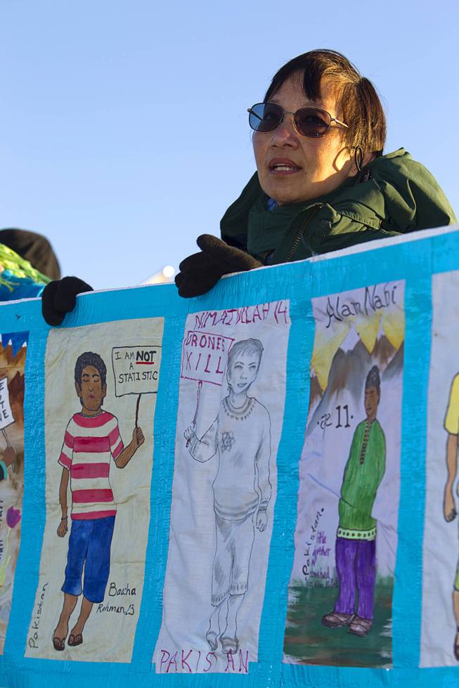 Bie Tan of the San Francisco Bay Area helps hold a banner representing children killed by drone strikes during an anti-drone protest at Creech Air Force Base, about 50 miles northwest of Las Vegas, March 6, 2015. About 100 people came out for the protest organized by the peace group CODEPINK. .