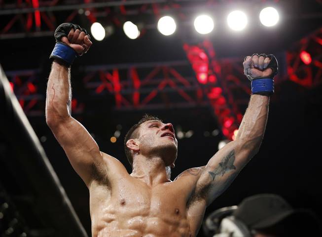 Rafael dos Anjos celebrates winning the men's lightweight mixed martial arts title bout against Anthony Pettis at UFC 185, early Sunday, March 15, 2015, in Dallas.