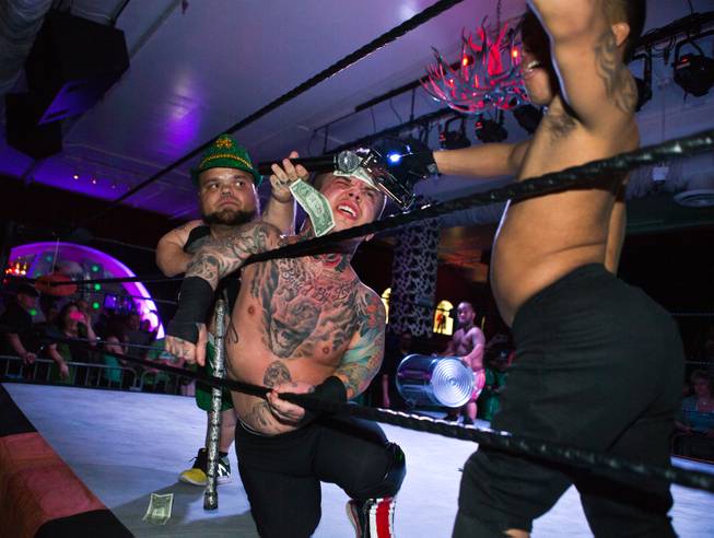 Wrestler Smalls has bills stapled to his forehead by opponent J-Mazing assisted by MC Turtle during their battle royal match in the St. Patricks Day Leprechaun Smackdown by Midgets Unleashed at the Fremont Country Club on Tuesday, March, 17, 2015.