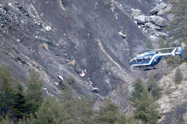 A rope hangs from a rescue helicopter flying past debris of the Germanwings passenger jet, scattered on the mountainside, near Seyne les Alpes, French Alps, Tuesday, March 24, 2015. A Germanwings passenger jet carrying at least 150 people crashed Tuesday in a snowy, remote section of the French Alps, sounding like an avalanche as it scattered pulverized debris across the mountain.