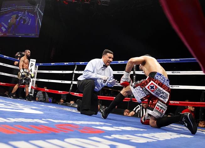 Referee Tony Weeks gives a count to WBC featherweight champion Jhonny Gonzalez of Mexico after he was knocked down in the fourth round by Gary Russell Jr., left, of Washington D.C. at the Palms Saturday, March 28, 2015. Russell took the title with a fourth-round TKO.