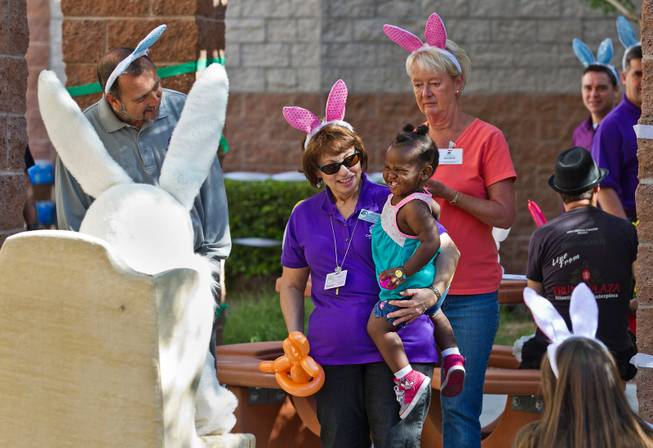 Mary Ralph with Catholic Charities of Southern Nevada introduces a child to the easter Bunny during an early holiday party for children in need, giving away more than 500 Easter baskets will be given to pre-registered clients on Saturday, March, 28, 2015.