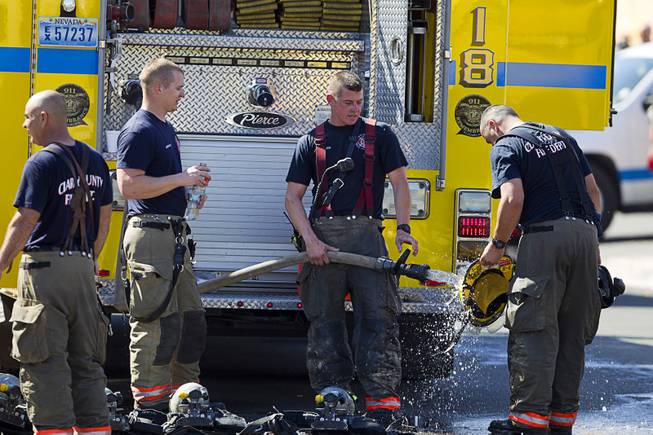 A firefighter washes his helmet after a two-alarm apartment fire near Tropicana and Eastern Avenue, March 30, 2015.